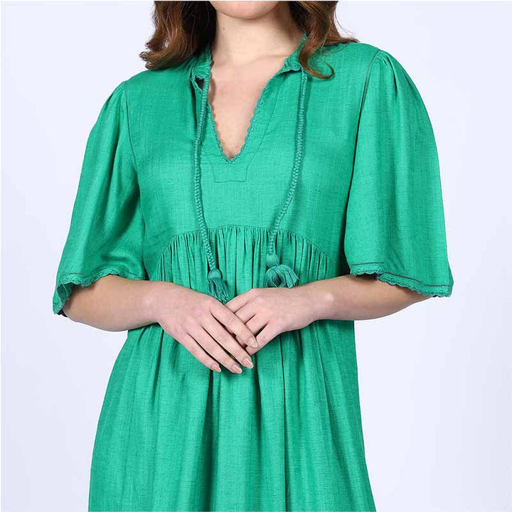 Close-up of the tasselled tie neckline on a green cotton midi dress.