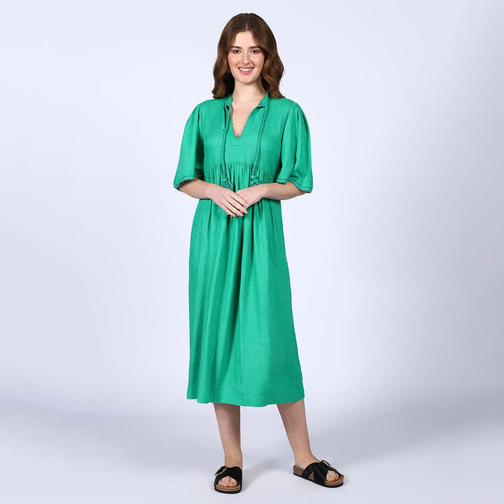 Woman wearing a green cotton slub midi dress with a tasselled tie neckline.