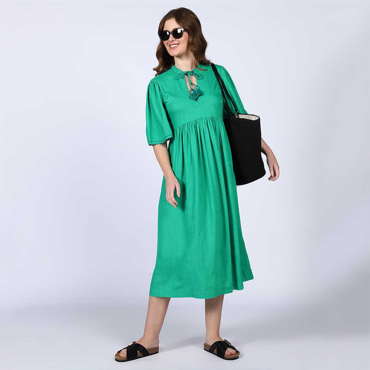 Woman wearing a green midi dress, carrying a black tote bag.