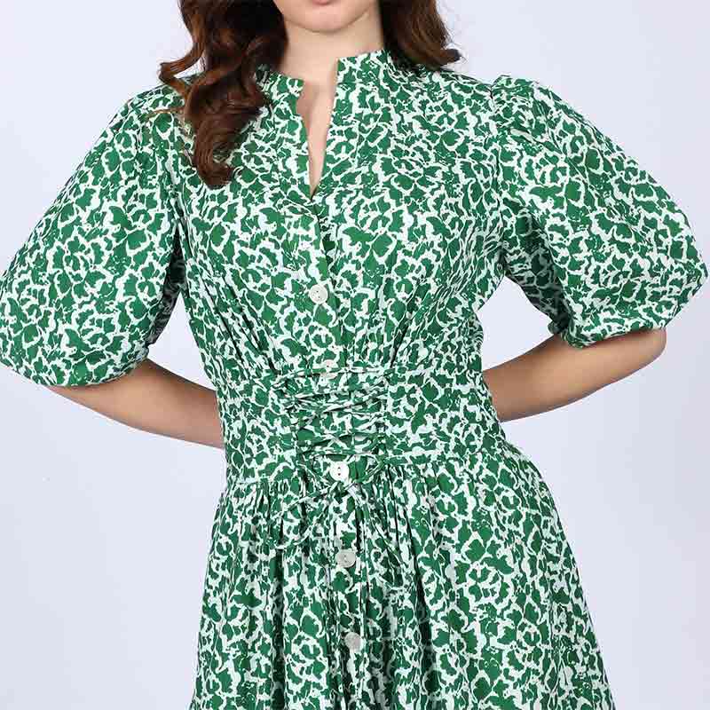Close-up of the tie waist and floral print on a green cotton dress.