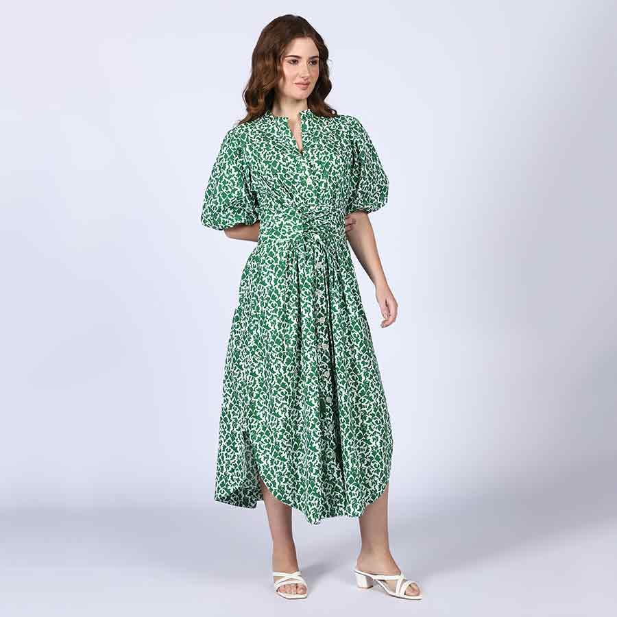 Full-length shot of a woman wearing a green floral-print cotton dress.