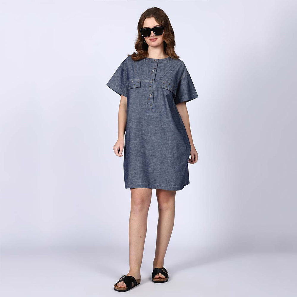 Woman wearing a grey chambray shirt dress, wearing sunglasses.