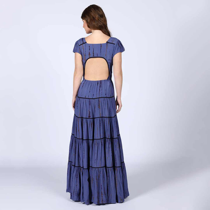 Back view of a woman wearing an indigo tiered viscose maxi dress.