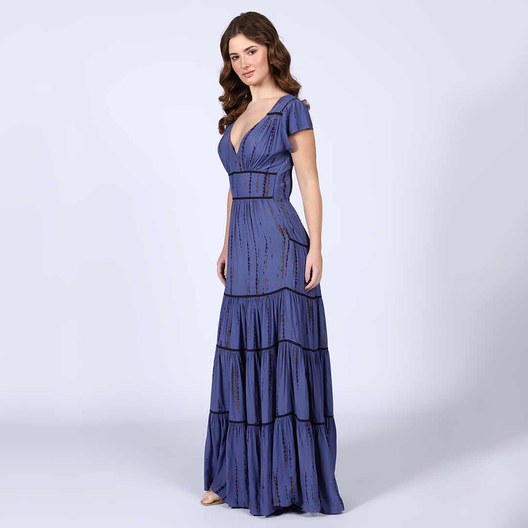 Full-length shot of a woman wearing an indigo tiered maxi dress.