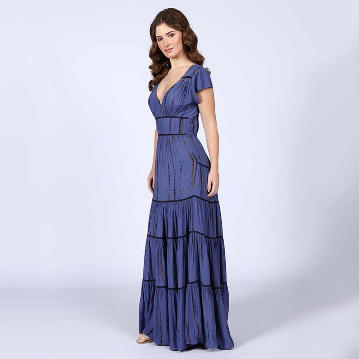 Full-length shot of a woman wearing an indigo tiered maxi dress.