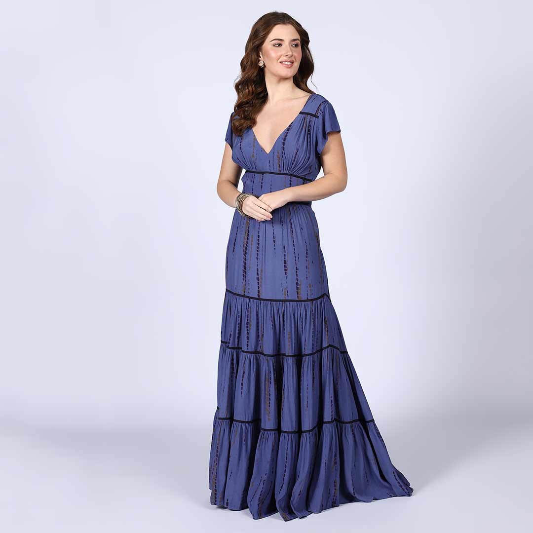 Side view of a woman wearing an indigo tiered maxi dress.