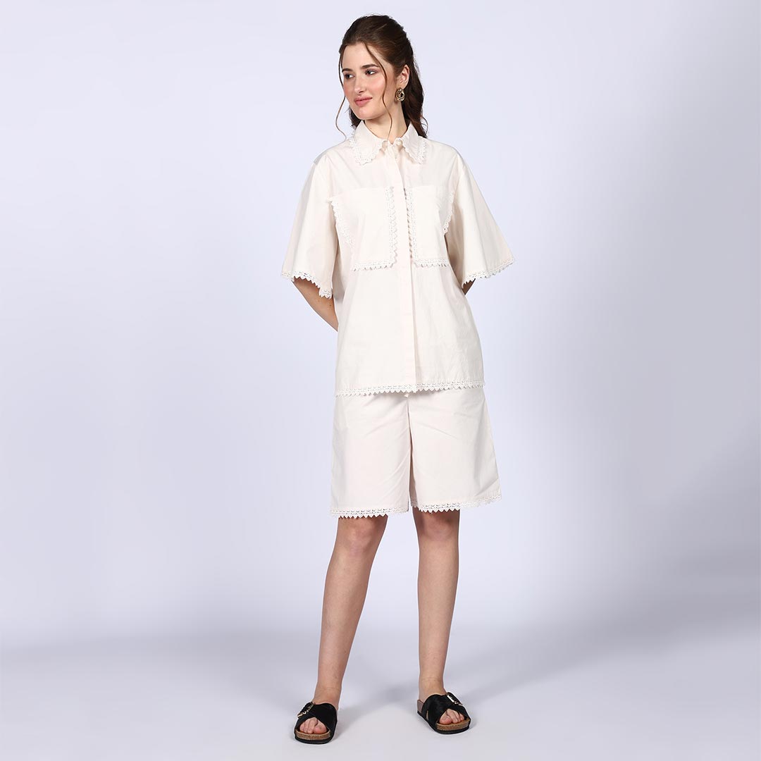 Woman wearing a solid ivory cotton poplin co-ord set with crochet-trimmed bell sleeves.