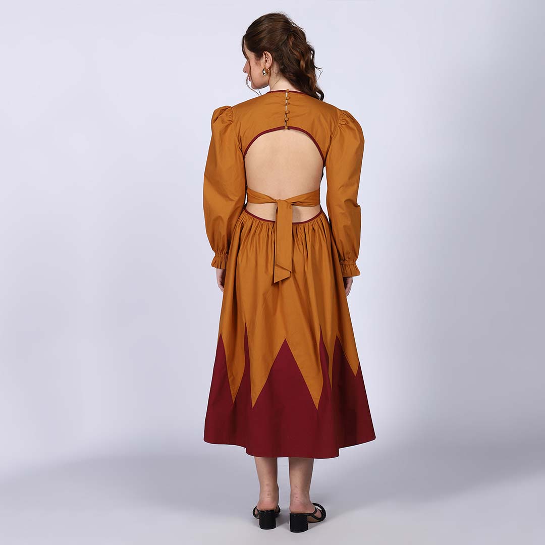Back view of a woman wearing a mustard dress with a keyhole cutout and tie.