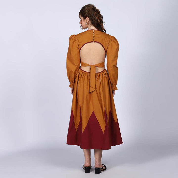 Back view of a woman wearing a mustard dress with a keyhole cutout and tie.
