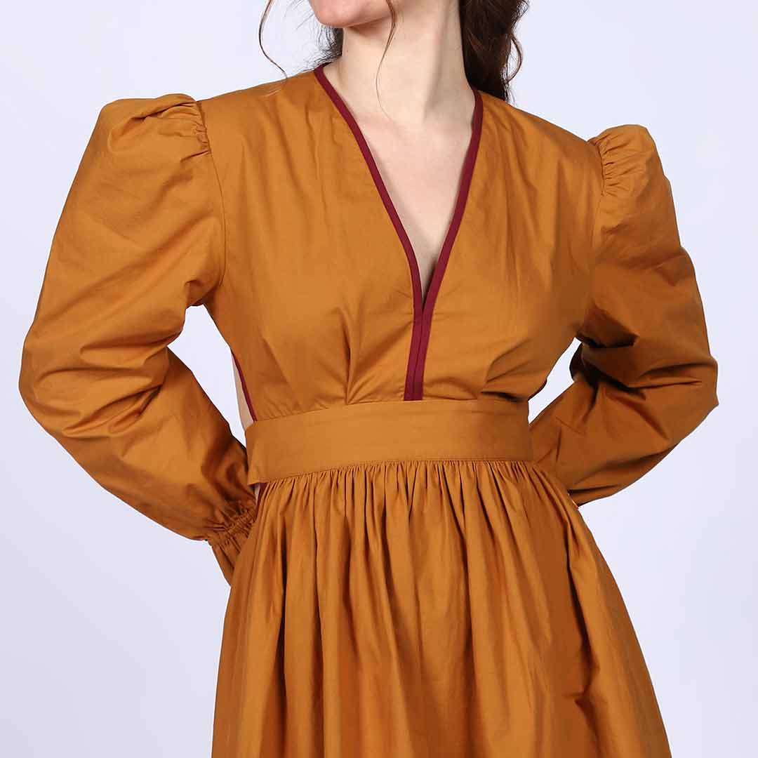 Close-up of the burgundy V-neck trim on a mustard midi dress.