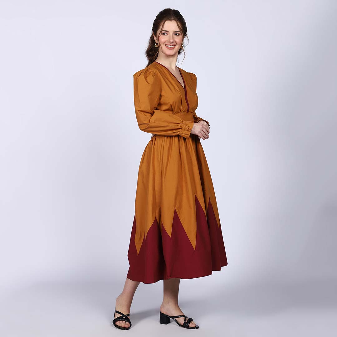 Side view of a woman wearing a mustard and burgundy midi dress.