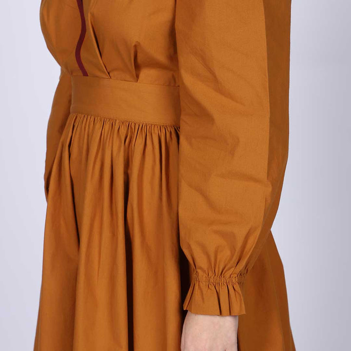 Close-up of the waist tie and gathered skirt on a mustard midi dress.