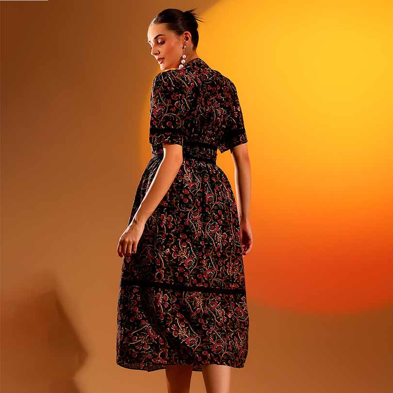 Full-length shot of a woman wearing a black dobby-print midi dress, mid-calf length.