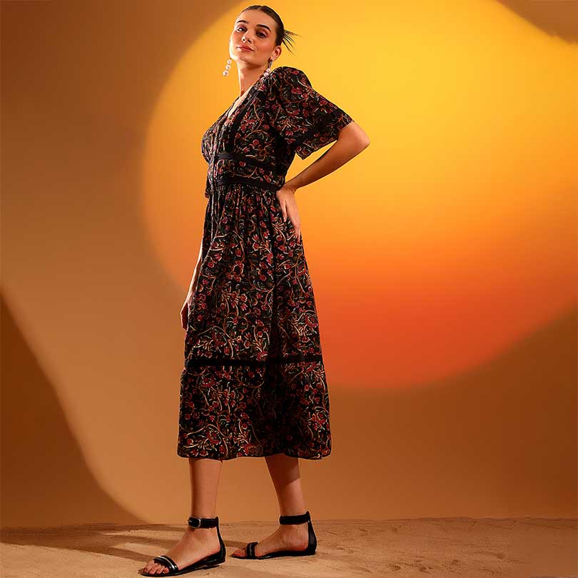 Side view of a woman wearing a black printed midi dress.