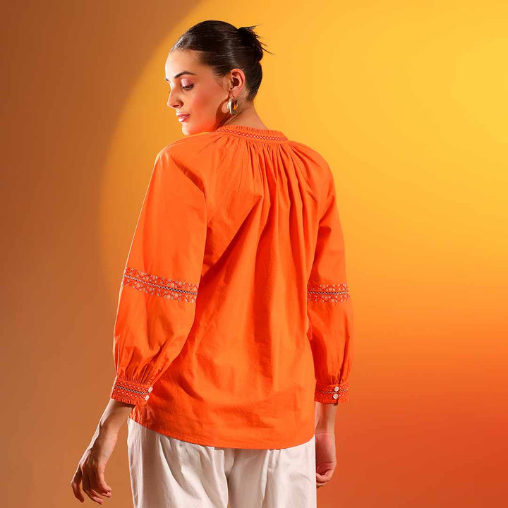Back view of a woman wearing an orange embroidered cotton shirt.