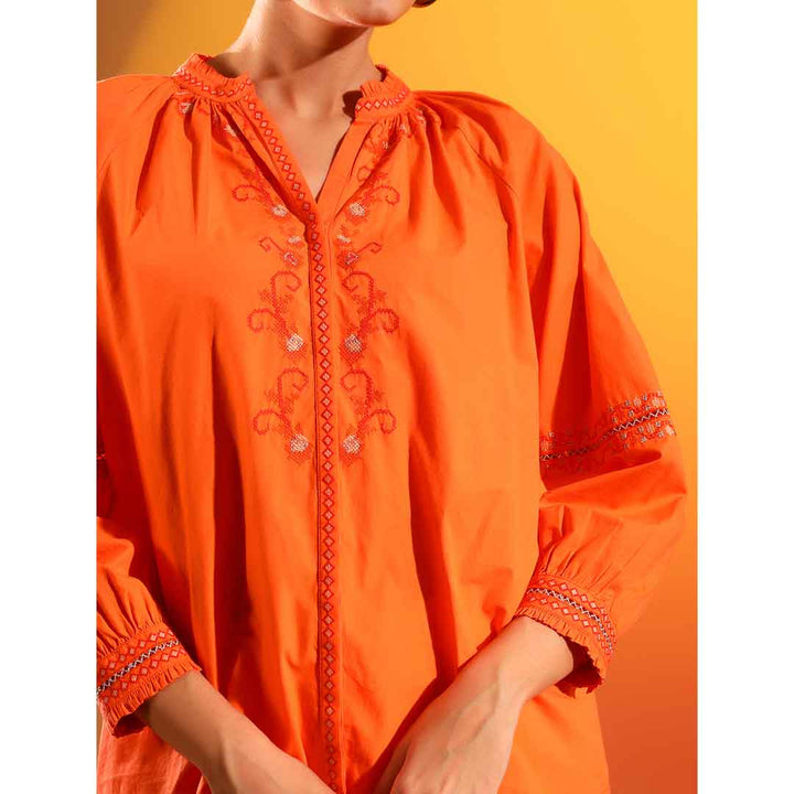 Close-up of the embroidered placket and collar detail on an orange cotton shirt.