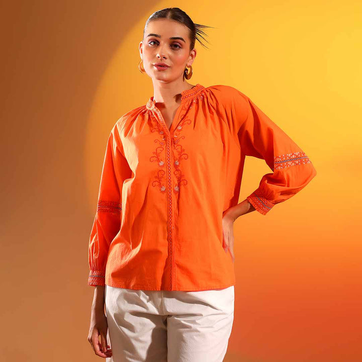 Woman wearing an orange cotton shirt with embroidered detailing.
