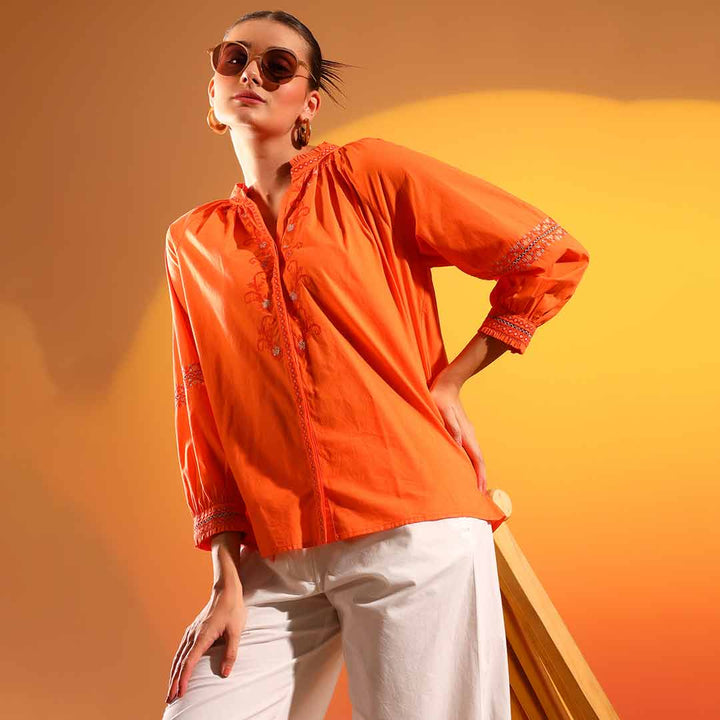 Alternate side view of a woman wearing an orange embroidered cotton shirt.