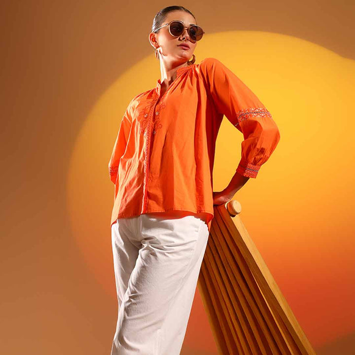 Side view of a woman wearing an orange embroidered cotton shirt.
