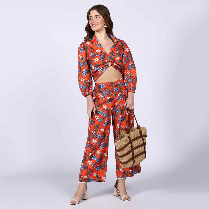Side view of a woman wearing an orange floral crop top and trouser co-ord.