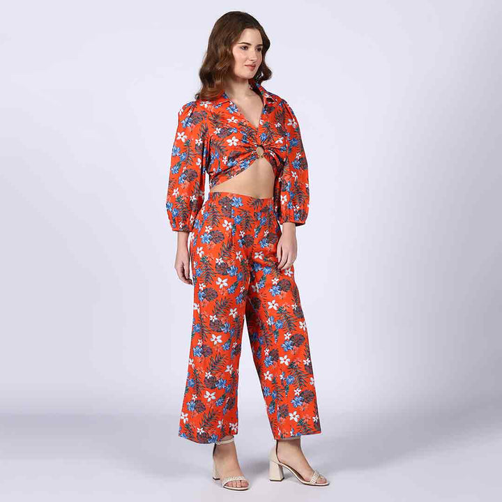 Woman wearing an orange floral co-ord set with a front waist tie detail.