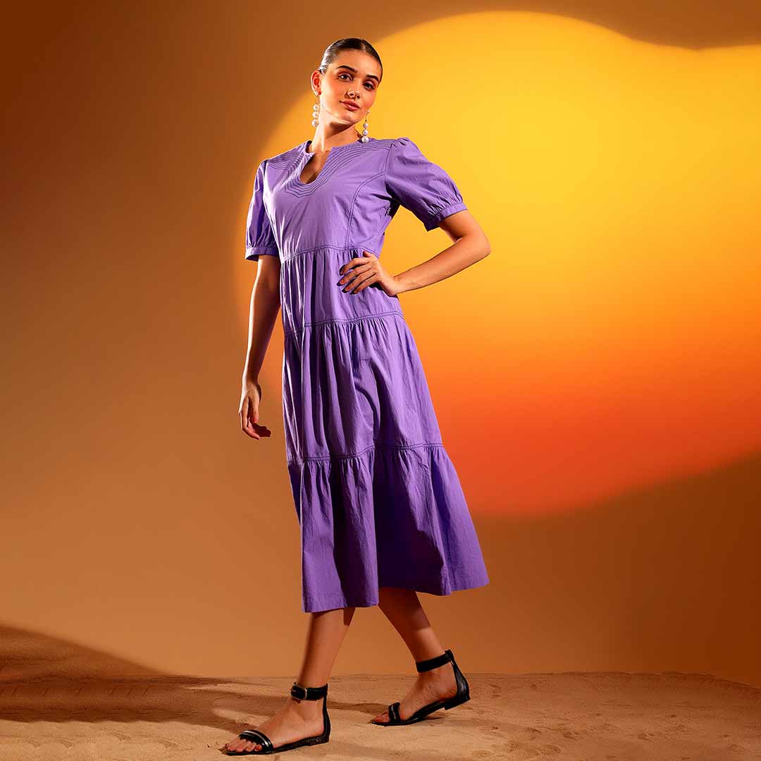 Side view of a woman wearing a purple/iris cotton midi dress, showing calf-length hem.