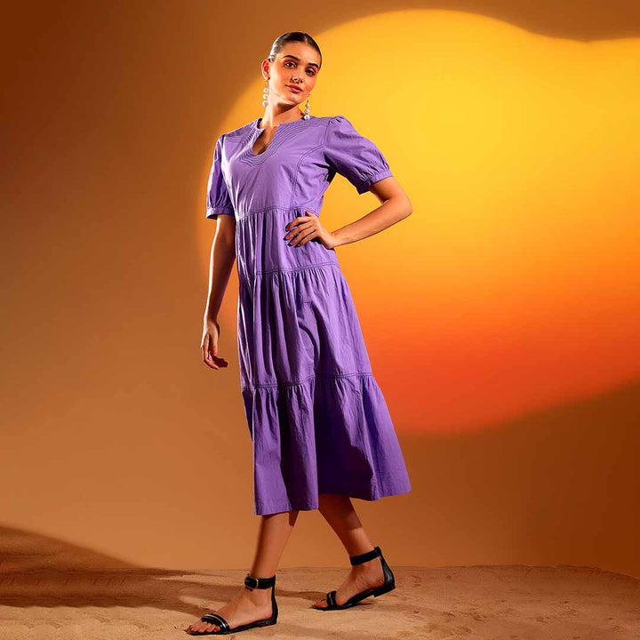 Side view of a woman wearing a purple/iris cotton midi dress, showing calf-length hem.