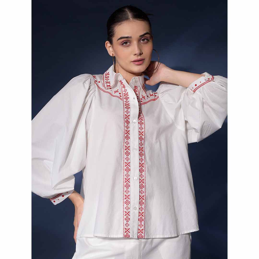 Close-up of the red embroidered collar and placket on a white cotton shirt.