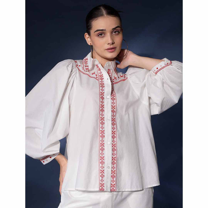 Close-up of the red embroidered collar and placket on a white cotton shirt.
