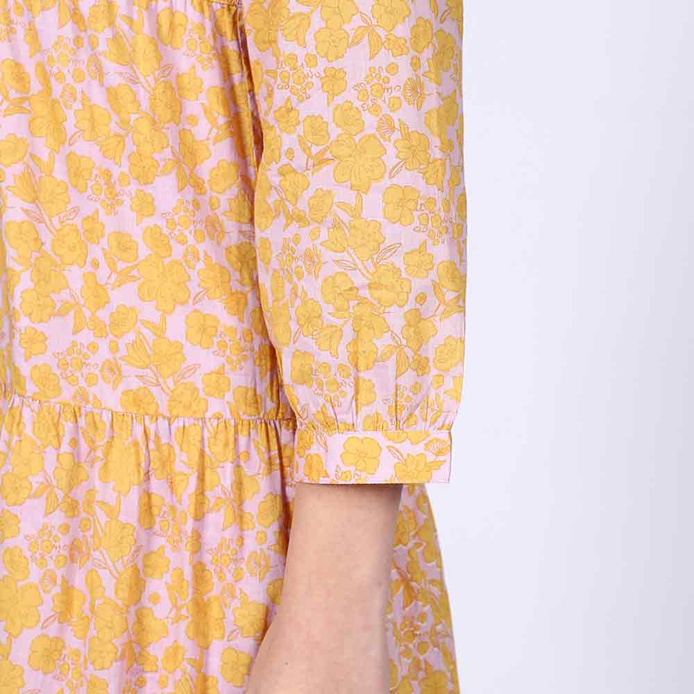 Back view of a woman wearing a yellow multicolour tiered midi dress.