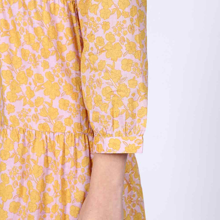 Back view of a woman wearing a yellow multicolour tiered midi dress.