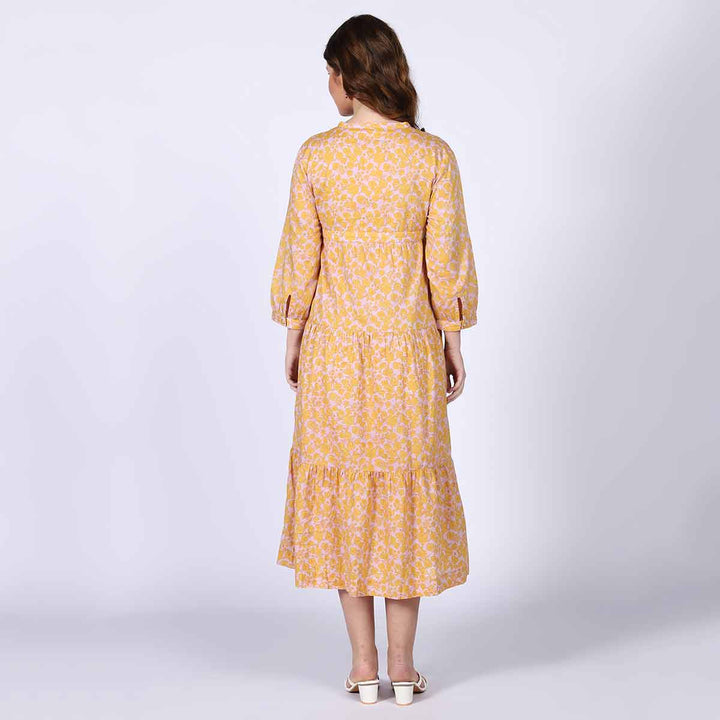 Close-up of the print and tiered hem on a yellow multicolour midi dress.