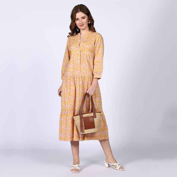 Woman wearing a yellow multicolour print tiered cotton midi dress.