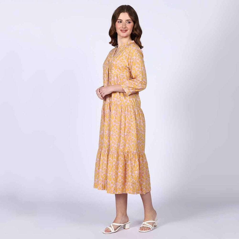Side view of a woman wearing a yellow multicolour tiered midi dress.