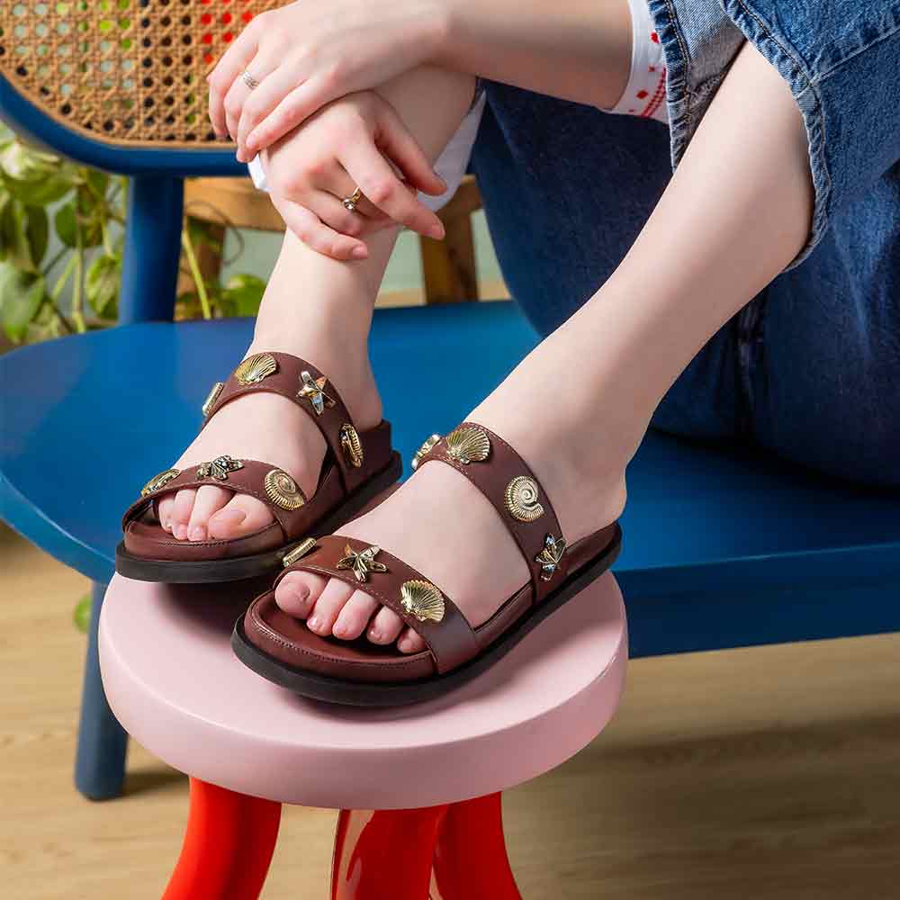 Woman wearing Saint Hallie brown leather seashell-studded footbed sandals