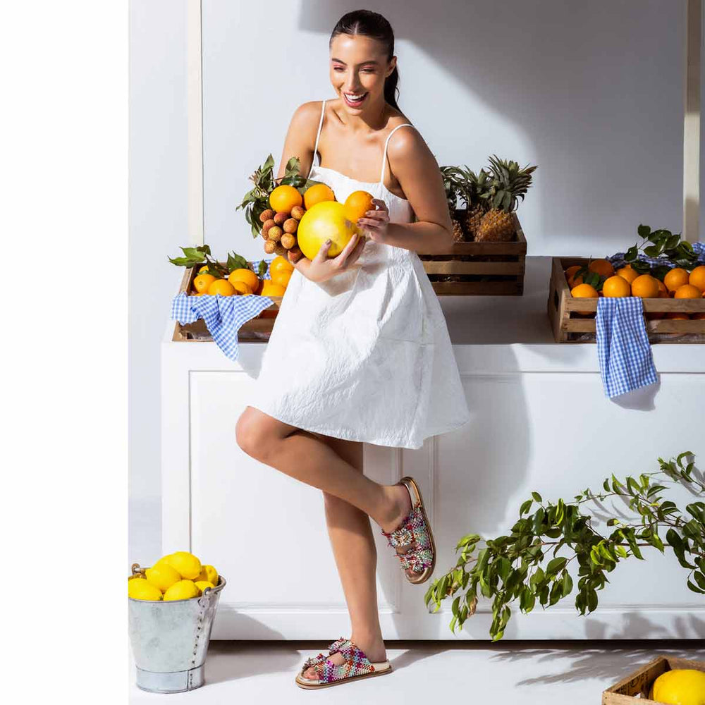 Woman in a white dress wearing footbed leather sandals from saint g uk