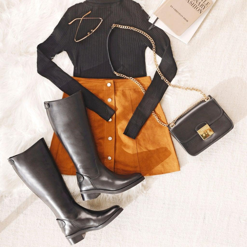 Women's black leather knee high boots by Saint Stella, styled flat-lay lifestyle shot